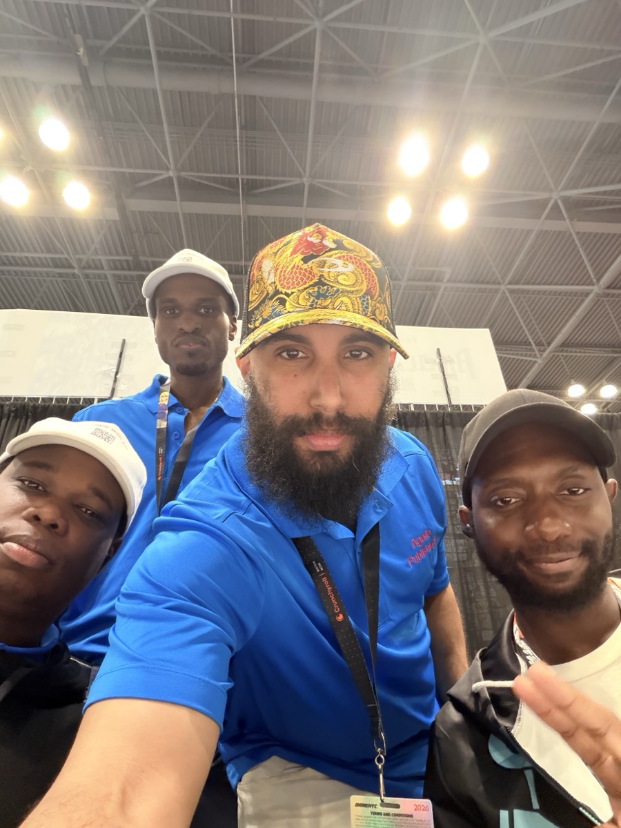 Four members of the Agada Publishings team together on the convention floor, three of them wearing blue Agada Publishings polo shirts.